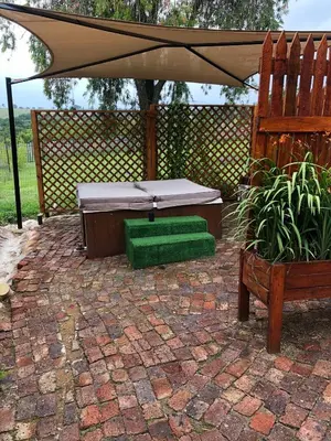 a patio with a hot tub and an umbrella at JB Countrylife Accommodation in Centurion