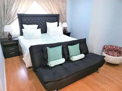 a bed with a black couch in a bedroom at JB Countrylife Accommodation in Centurion