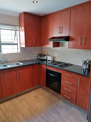 a kitchen with wooden cabinets and a black stove top oven at JB Countrylife Accommodation in Centurion