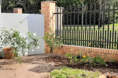 a wrought iron fence with a garden with flowers at Kruger Southern Cross in Malelane