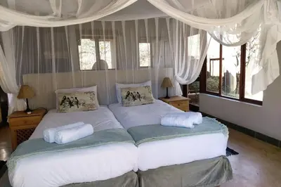 a bedroom with a large bed with white sheets and pillows at 13 Raptors Lodge in Hoedspruit