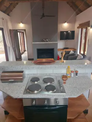 a kitchen with a stove top oven next to a living room at 13 Raptors Lodge in Hoedspruit