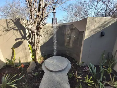 a fountain in a garden next to a building at 13 Raptors Lodge in Hoedspruit