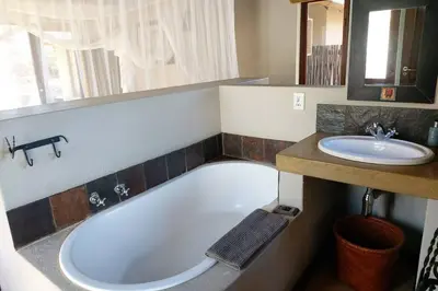 a bathroom with a tub and a sink at 13 Raptors Lodge in Hoedspruit