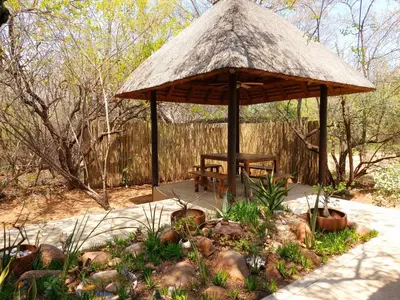 a wooden gazebo with a chair and a table at 13 Raptors Lodge in Hoedspruit