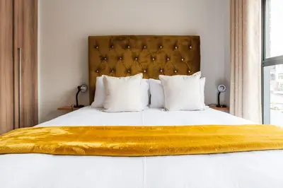 a bedroom with a large bed with a yellow blanket on it at #Alimama Spaces Blyde Haven in Pretoria