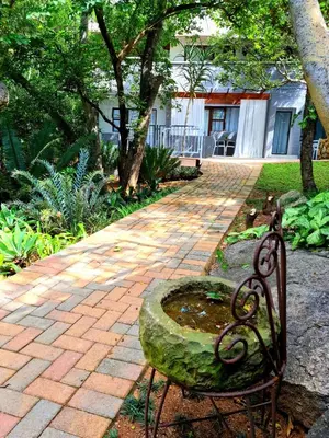 a bench sitting on a brick walkway in a yard at Forget me not Selfcatering Apartments in Nelspruit