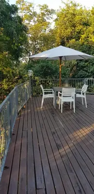 a wooden deck with a table and an umbrella at Forget me not Selfcatering Apartments in Nelspruit