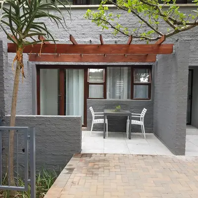 a patio with a table and chairs in a building at Forget me not Selfcatering Apartments in Nelspruit