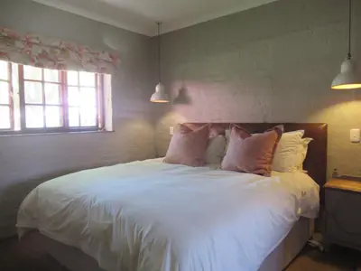 a bedroom with a bed with white sheets and pillows at Critchley Hackle - Leisure rooms in Dullstroom