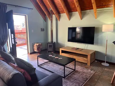 a living room with a couch and a flat screen tv at Camdeboo Place in Dullstroom