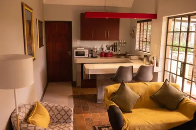 a living room with a yellow couch and a kitchen at Camdeboo Place in Dullstroom