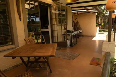a patio with a wooden table and chairs on a porch at Camdeboo Place in Dullstroom