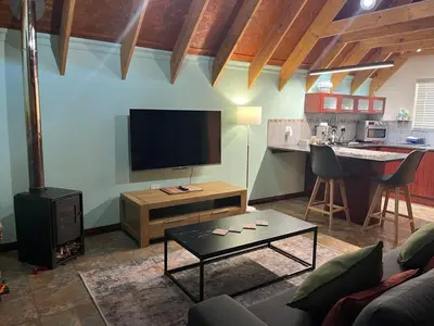 a living room with a flat screen tv and a table at Camdeboo Place in Dullstroom