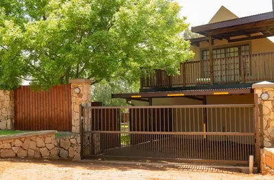 a gate in front of a house with a tree at Camdeboo Place in Dullstroom