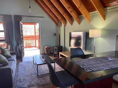 a living room with a table and chairs and a tv at Camdeboo Place in Dullstroom