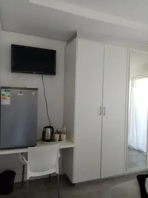 a room with a desk and a tv on the wall at Lior-Gil accommodation- in Kempton Park