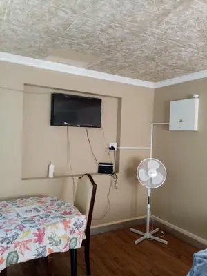 a bedroom with a table and a tv on the ceiling at Lior-Gil accommodation- in Kempton Park