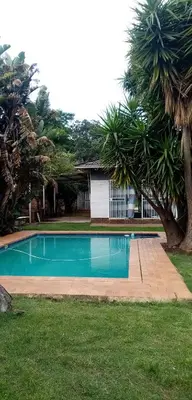 a swimming pool in a yard with palm trees at Lior-Gil accommodation- in Kempton Park