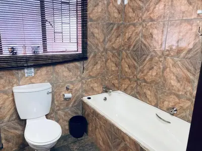 a bathroom with a toilet and a bath tub at Ivory Sands Selfcatering house in Marloth Park