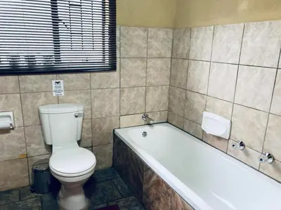 a bathroom with a toilet and a bath tub at Ivory Sands Selfcatering house in Marloth Park