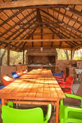 a large wooden table with colorful chairs in front of a fireplace at Ivory Sands Selfcatering house in Marloth Park