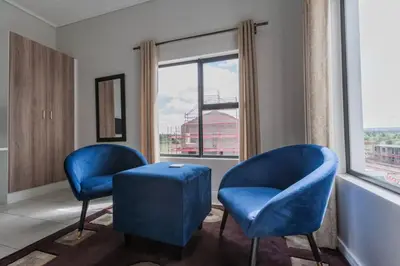 two blue chairs in a room with a window at Alimama Spaces: The Manson's Green Creek Studio in Pretoria