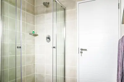 a shower with a glass door in a bathroom at Alimama Spaces: The Manson's Green Creek Studio in Pretoria