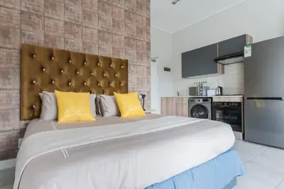a bedroom with a large bed with yellow pillows at Alimama Spaces: The Manson's Green Creek Studio in Pretoria