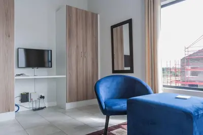 a living room with a blue chair and a television at Alimama Spaces: The Manson's Green Creek Studio in Pretoria