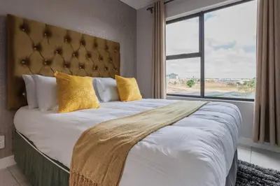 a bedroom with a large bed with a large window at Alimama Spaces: The Manson's Green Creek in Pretoria
