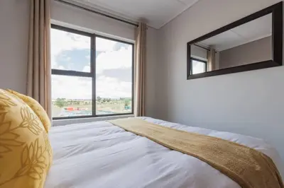 a bedroom with a bed with a mirror and a window at Alimama Spaces: The Manson's Green Creek in Pretoria