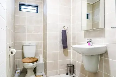 a white bathroom with a toilet and a sink at Alimama Spaces: The Manson's Green Creek in Pretoria