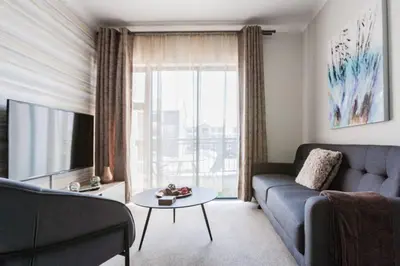 a living room with a blue couch and a tv at #Alimama Spaces The Fountain Blyde in Pretoria