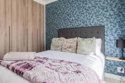 a bedroom with a large bed with purple and blue wallpaper at #Alimama Spaces The Fountain Blyde in Pretoria
