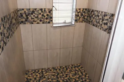 a bathroom with a shower with a window at Koemi Guest House in Kempton Park