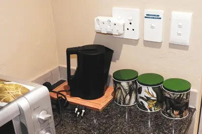 a kitchen with a counter with three drums on a shelf at Koemi Guest House in Kempton Park