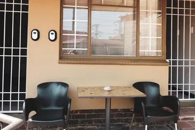 two chairs and a table in front of a building at Koemi Guest House in Kempton Park