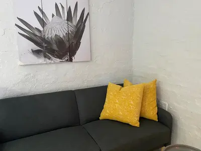 a black couch with yellow pillows in a living room at Centurion Fully furnished lock up&go 1 bedroom apartment in Centurion