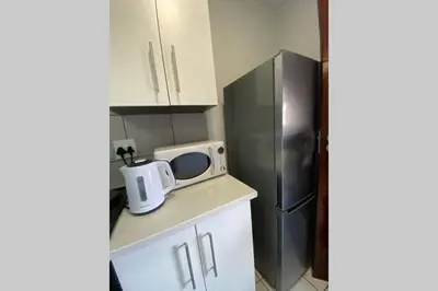 a kitchen with a microwave and a refrigerator at Centurion Fully furnished lock up&go 1 bedroom apartment in Centurion