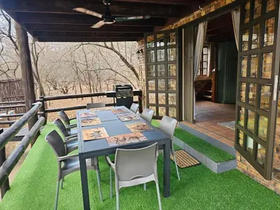 a table and chairs on a patio with grass at Inkwazi Place in Marloth Park