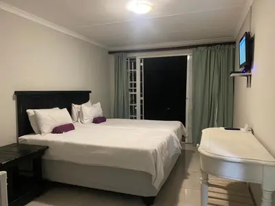 a bedroom with a large white bed and a window at Ndzuti Guest House in Witbank