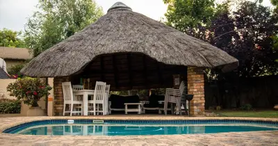 a gazebo with chairs and a table and a pool at Ndzuti Guest House in Witbank