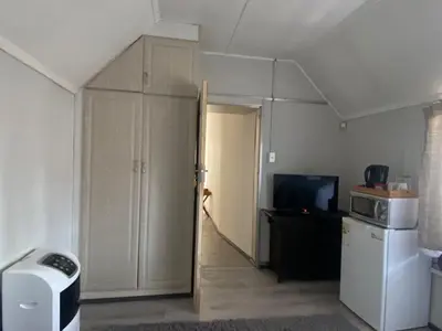 a room with a kitchen with a door and a refrigerator at Ndzuti Guest House in Witbank