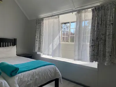 a bedroom with a bed and a window with curtains at Ndzuti Guest House in Witbank