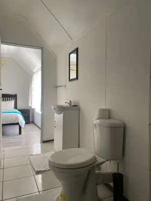 a white bathroom with a toilet and a sink at Ndzuti Guest House in Witbank