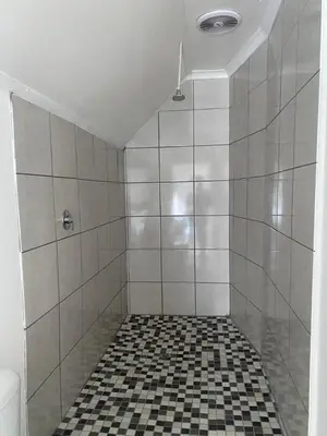a shower with a black and white tiled floor at Ndzuti Guest House in Witbank