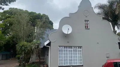 a white house with a large window on the side of it at Ndzuti Guest House in Witbank
