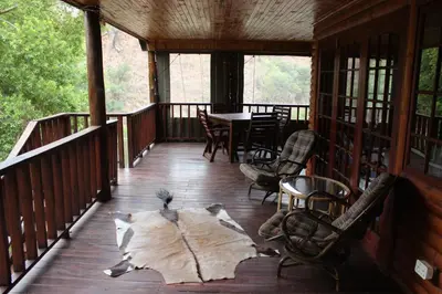 a porch of a cabin with a table and chairs at Wilgeboomsdrift Safaris in Modimolle