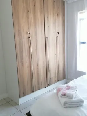 a bedroom with a wooden cabinet with towels on a bed at The Blyde Riverwalk estate, Crystal Lagoon in Pretoria